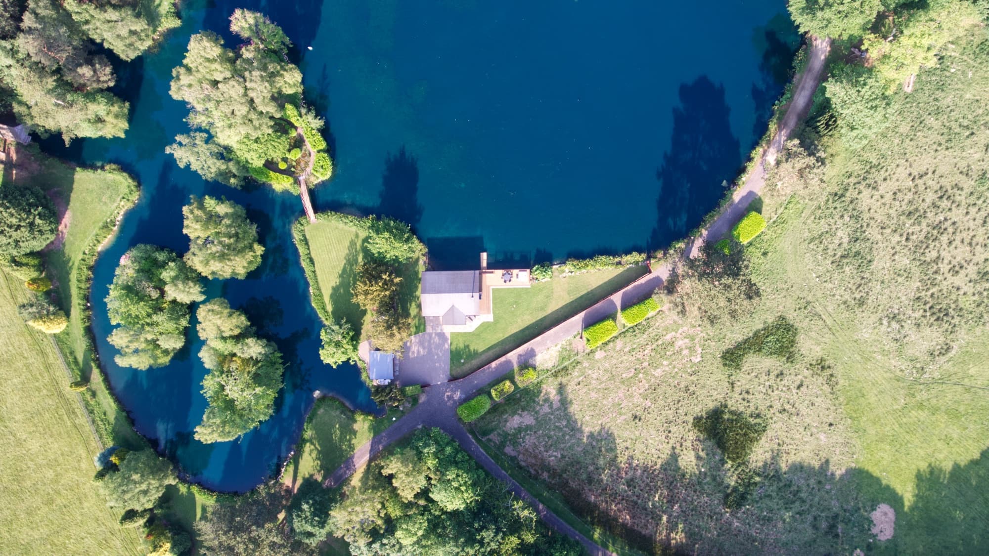 The lodge, lawn and deck from directly overhead, tucked between the lake and open fields
